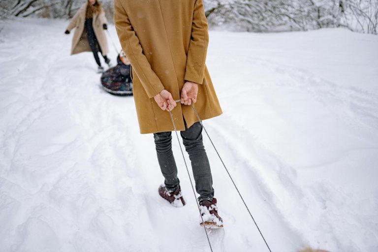 A person pulls a sled with a child through a snowy winter landscape, enjoying outdoor fun.